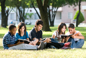 School children reading books in the grass